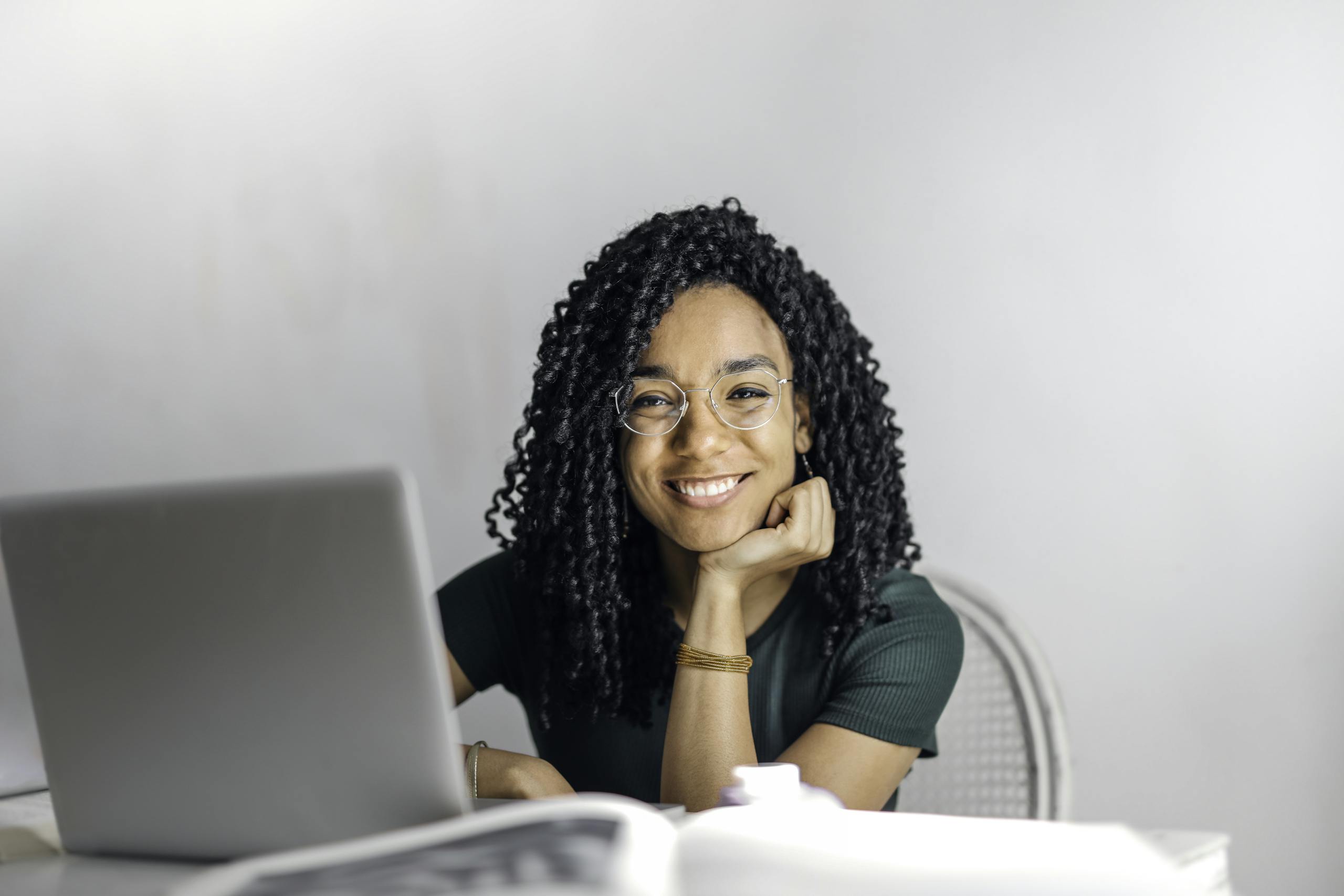 Joyful nonprofit professional with curly hair smiling in front of laptop because she hired a bookkeeper.