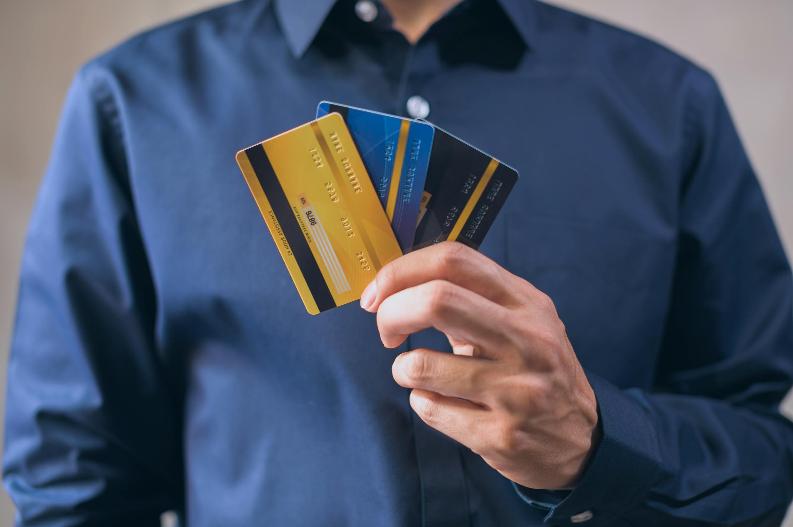 Person holding three credit cards, symbolizing separate accounts for each of their businesses.